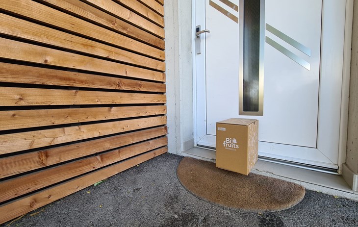 Le Shop en ligne livraison à domicile - Une photo d'un carton Biofruits posé devant une porte d'entrée de maison