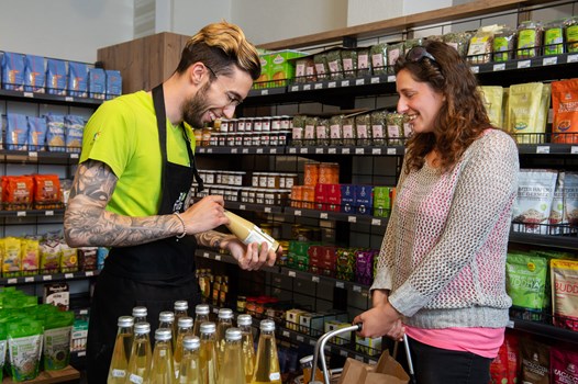 Service au Shop Sion  - Une image d'un vendeur et d'une cliente discutant au milieu des produits dans le Shop de Sion