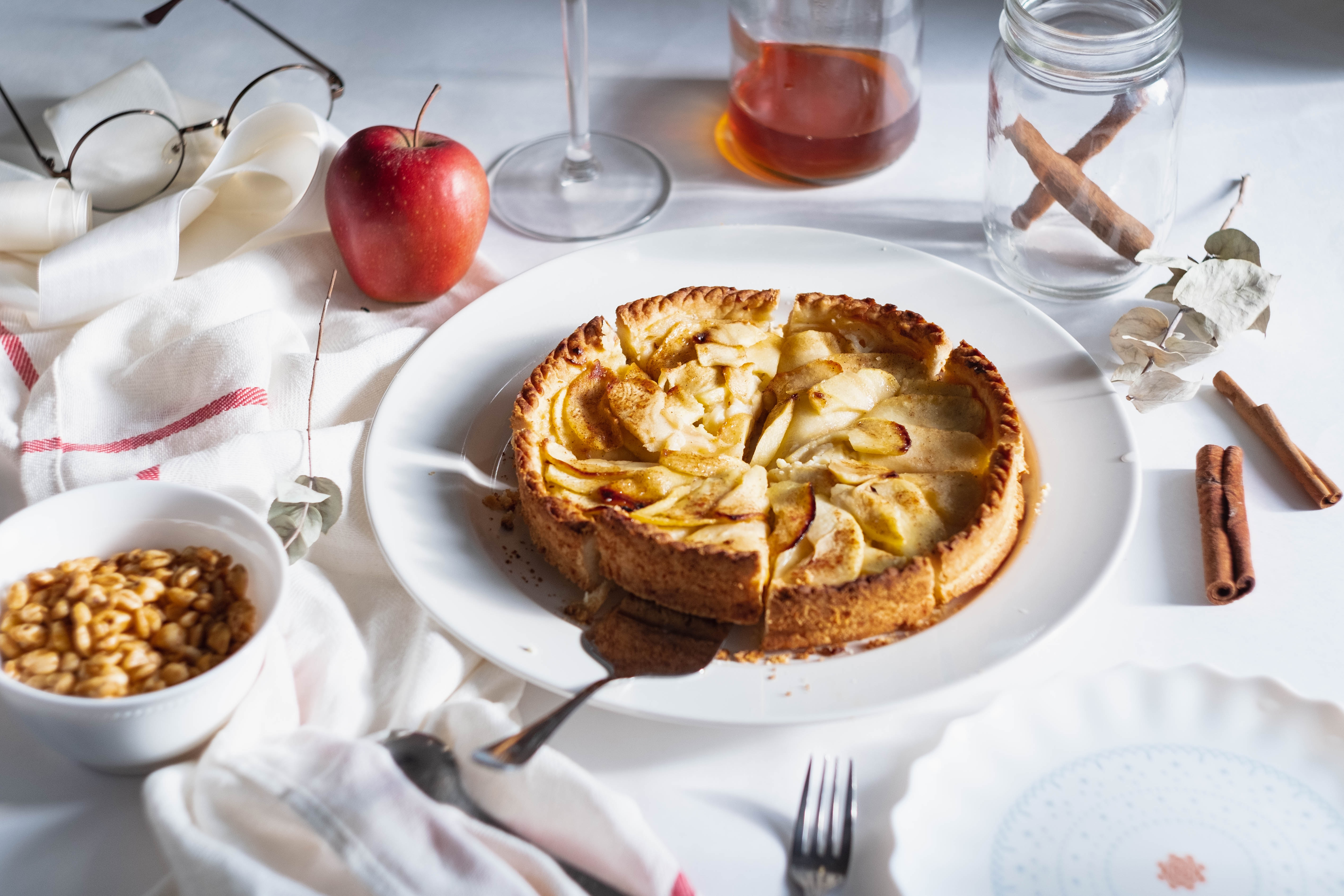 Tarte aux pommes Biofruits - Une photo d'une tarte aux pommes sur une table avec une nappe blanche et avec des ingrédients partout