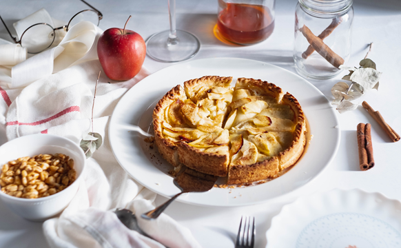 Tarte aux pommes Biofruits - Une photo d'une tarte aux pommes sur une table avec une nappe blanche et avec des ingrédients partout
